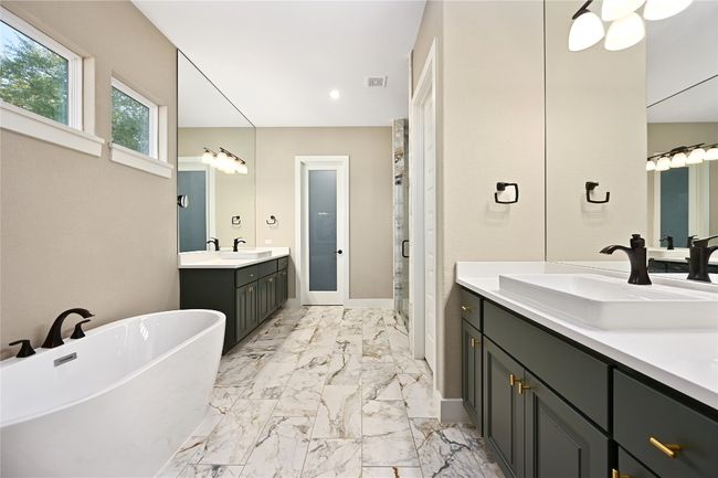 Full bathroom featuring a freestanding tub, two vanities | Image 16