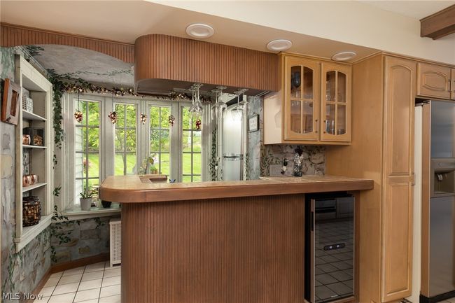 Kitchen featuring backsplash, stainless steel fridge, wine cooler, and light tile floors | Image 25
