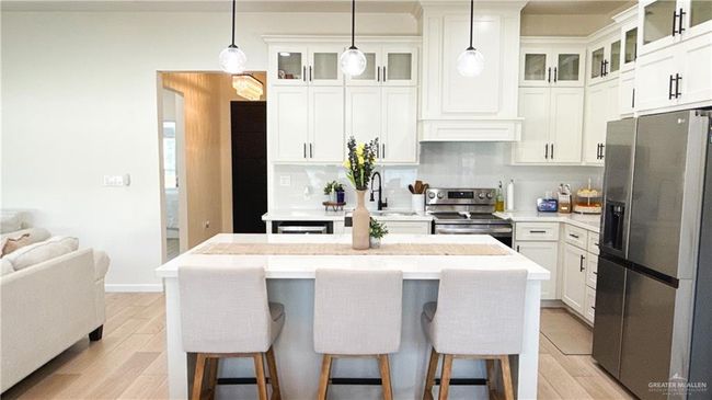 Kitchen featuring appliances with stainless steel finishes, light wood-type flooring, light countertops, and a kitchen bar | Image 10