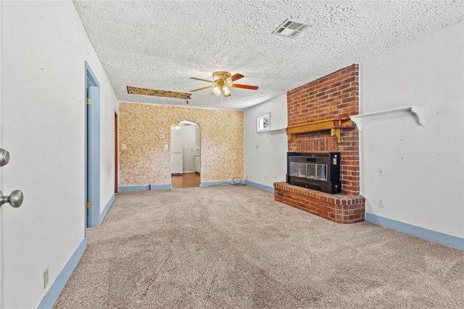 Unfurnished living room with carpet floors, a fireplace, a textured ceiling, and ceiling fan | Image 10