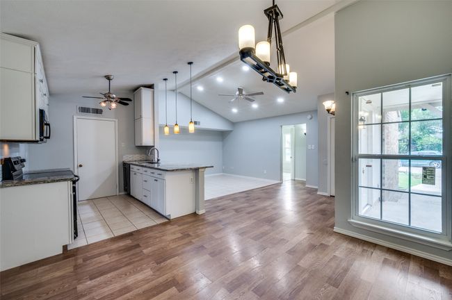 Kitchen featuring a ceiling fan, electric stove, lofted ceiling, stainless steel microwave, and white cabinetry | Image 6