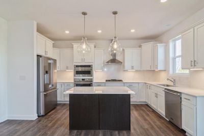 Photo is of the actual home. This spacious gourmet kitchen features a large center island, quartz countertops, LVP floors, stainless appliances and more. | Image 2