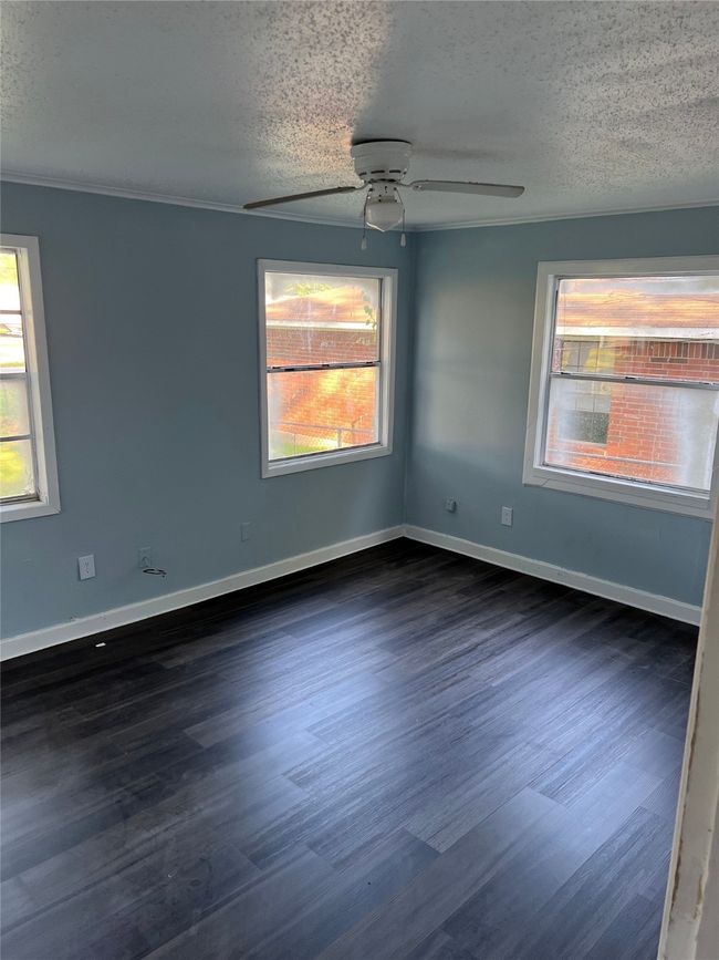 Unfurnished room with a textured ceiling, dark wood-style flooring, ceiling fan, and baseboards | Image 4