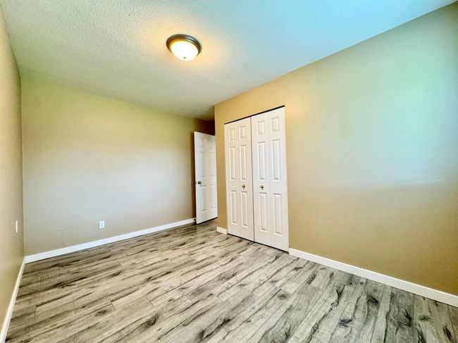 Unfurnished bedroom with wood finished floors, a closet, and a textured ceiling | Image 15