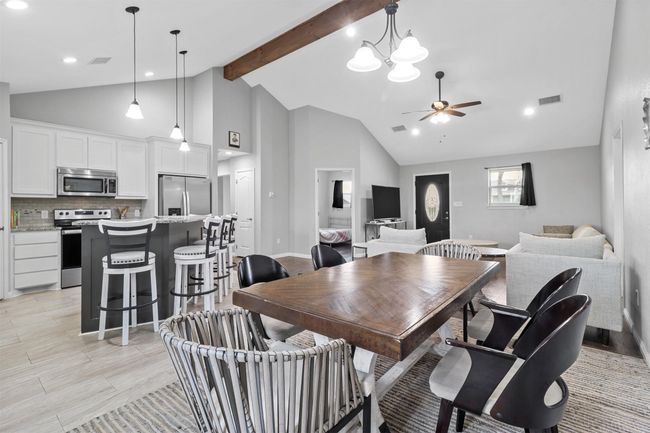 Dining room featuring beam ceiling, high vaulted ceiling, ceiling fan with notable chandelier, and visible vents | Image 9