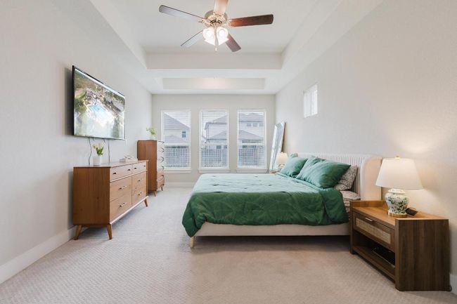 Primary bedroom with high tray ceilings, ceiling fan and large windows | Image 13