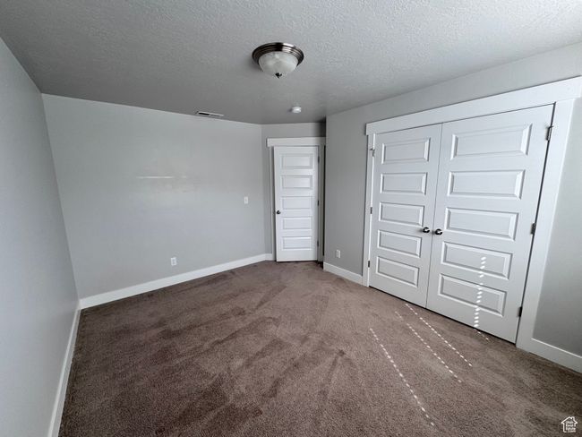 Unfurnished bedroom featuring baseboards, visible vents, a textured ceiling, and carpet | Image 24