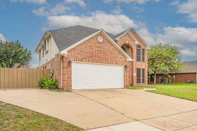 Traditional home with brick siding, driveway, an attached garage, and a shingled roof | Image 39
