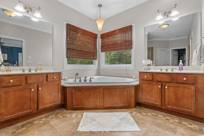 Bathroom featuring two vanities, a bath, inlaid floor details, and crown molding | Image 28