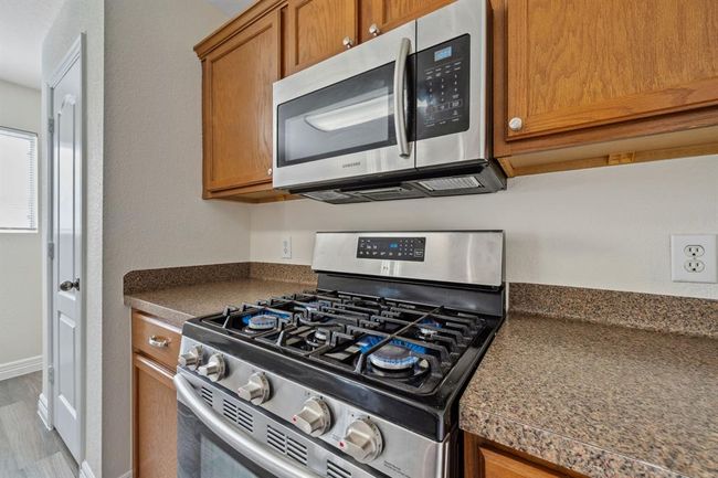 Kitchen features gas range and built-in microwave. | Image 12