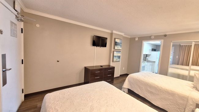 Bedroom with dark wood-style floors, a textured ceiling, crown molding, and ensuite bathroom | Image 6