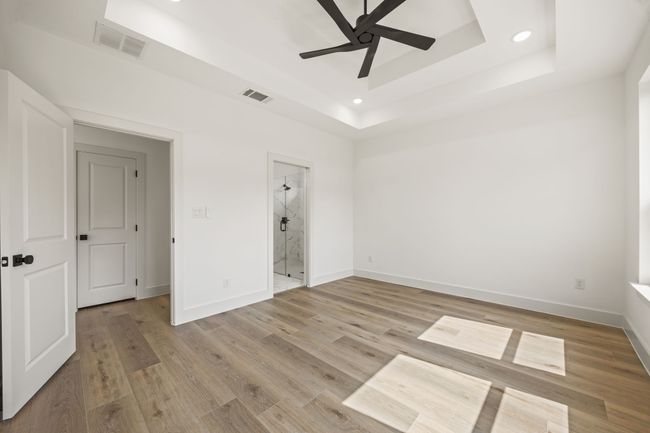 Unfurnished bedroom featuring a raised ceiling, baseboards, recessed lighting, light wood-style flooring, and connected bathroom | Image 17