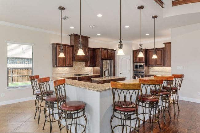 Kitchen featuring tasteful backsplash, a spacious island, baseboards, appliances with stainless steel finishes, and a breakfast bar area | Image 19