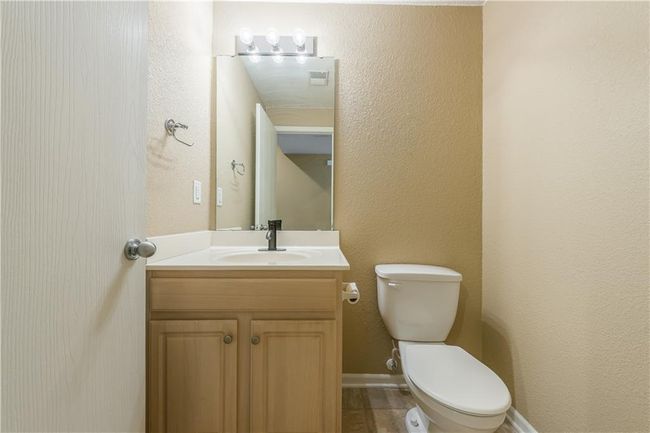 Half bath featuring vanity, toilet, a textured wall, and baseboards | Image 7
