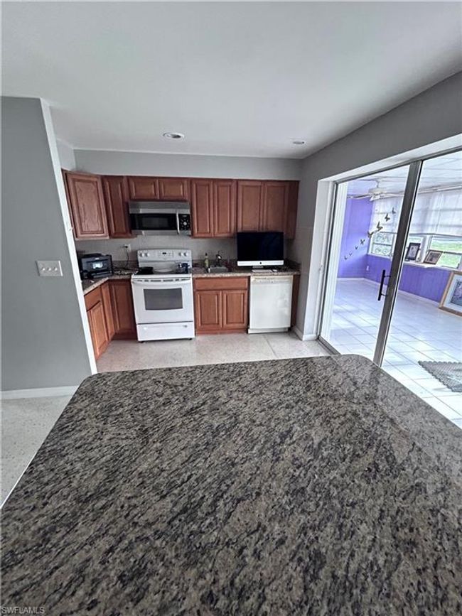Kitchen with white appliances, ceiling fan, and sink | Image 5
