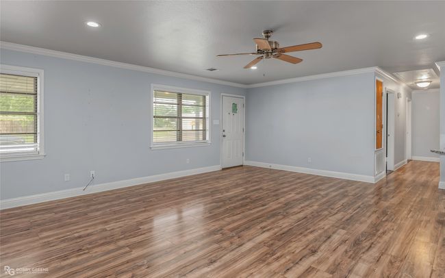Empty room featuring wood finished floors, ornamental molding, baseboards, visible vents, and a ceiling fan | Image 8