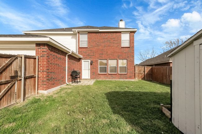 Back of property featuring a chimney, a fenced backyard, brick siding, and a lawn | Image 16