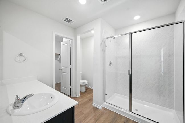 Full bathroom with a shower stall, wood finished floors, vanity, recessed lighting, and a walk in closet | Image 17