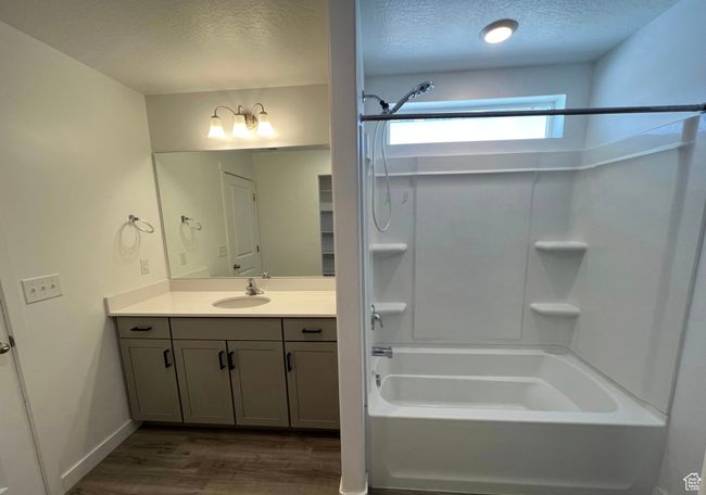 Full bathroom featuring a textured ceiling, wood finished floors, tub / shower combination, and vanity | Image 15