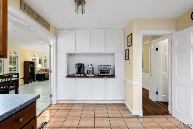 Kitchen featuring light tile patterned flooring, white cabinetry, dark countertops, and ceiling fan | Image 15