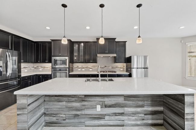 Kitchen featuring appliances with stainless steel finishes, light countertops, decorative backsplash, and a sink | Image 15