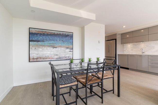 Kitchen featuring light wood-style floors, modern cabinets, light countertops, backsplash, and appliances with stainless steel finishes | Image 9