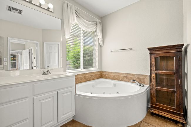 Bathroom with visible vents, tile patterned flooring, a whirlpool tub, and vanity | Image 16