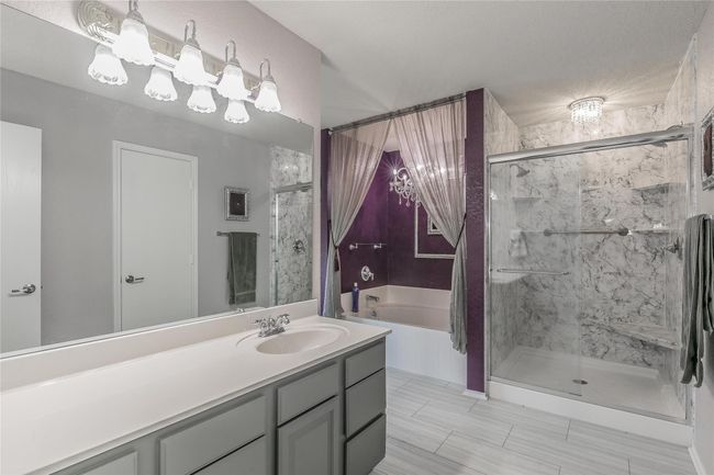 Full bath featuring a garden tub, a shower stall, vanity, and a chandelier | Image 10
