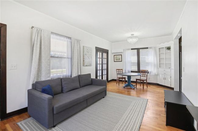 Living room featuring a notable chandelier, a healthy amount of sunlight, light wood-style floors, and a wall mounted air conditioner | Image 5