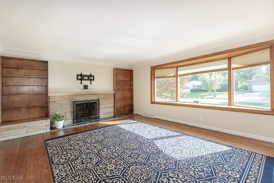 Family room with built in bookcases, and a stone surround wood burning fireplace. | Image 3