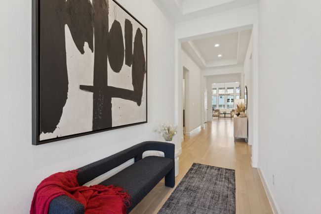 Hall with wood finished floors, a raised ceiling, recessed lighting, and baseboards | Image 13