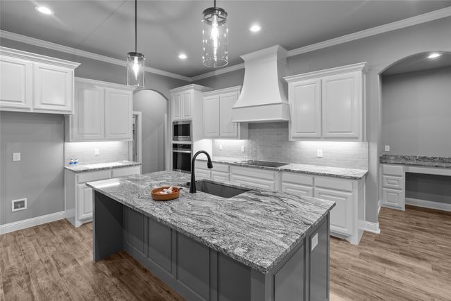 Kitchen featuring arched walkways, stainless steel appliances, custom exhaust hood, white cabinetry, and recessed lighting | Image 10