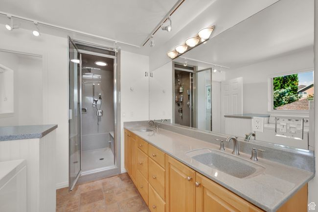 Steam Shower, master bath featuring track lighting, double vanity, a shower stall, baseboards, and stone finish flooring | Image 16
