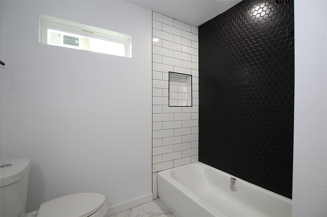Bathroom featuring washtub / shower combination, marble finish floor, baseboards, and toilet | Image 11