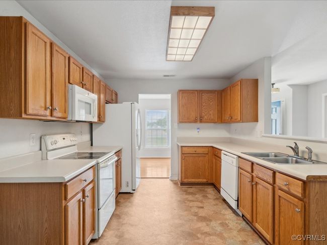 Kitchen featuring white appliances, light countertops, light floors, and brown cabinetry | Image 16