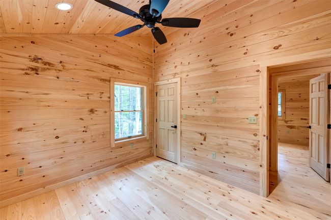 Spare room featuring wood walls, wooden ceiling, ceiling fan, and light wood-style flooring | Image 30