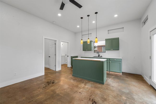 Kitchen with green cabinets, a kitchen island, a sink, ceiling fan, and finished concrete floors | Image 32