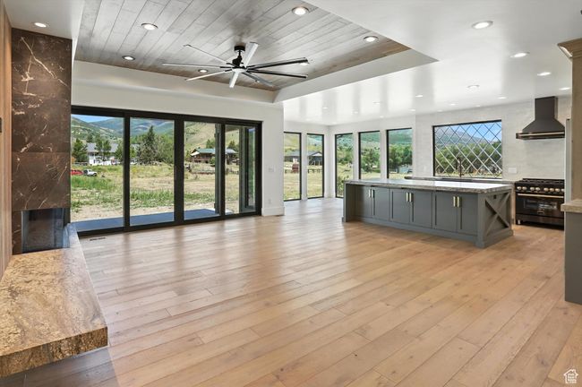 Unfurnished living room featuring wooden ceiling, recessed lighting, ceiling fan, light wood finished floors, and a high end fireplace | Image 4