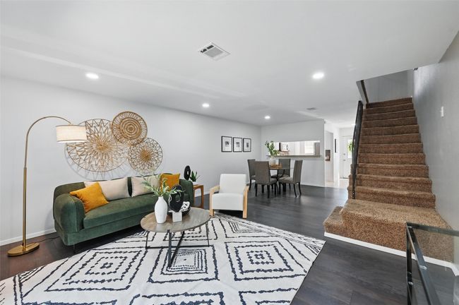 Living room with visible vents, baseboards, recessed lighting, wood finished floors, and stairs | Image 8
