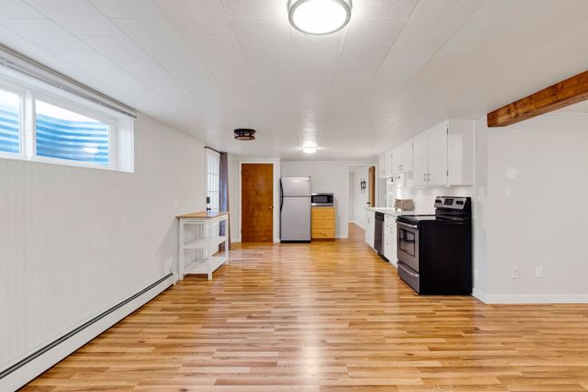 Below grade area featuring wood walls, baseboard heating, light wood-style flooring, and baseboards | Image 24