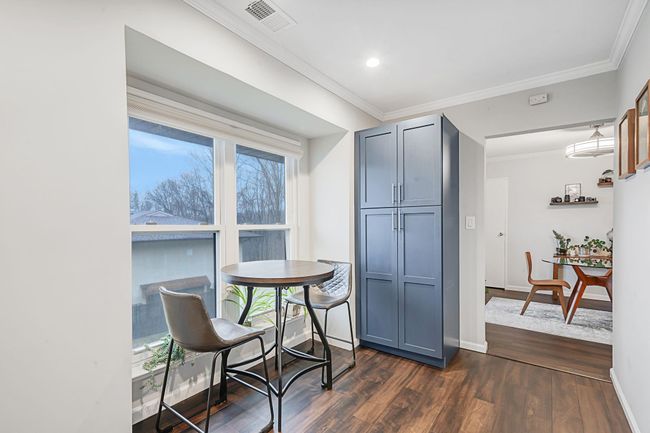 Dining area featuring ornamental molding, dark wood-type flooring, a healthy amount of sunlight, and visible vents | Image 16