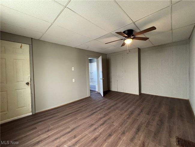 Spare room with dark wood-type flooring, a paneled ceiling, visible vents, and ceiling fan | Image 9
