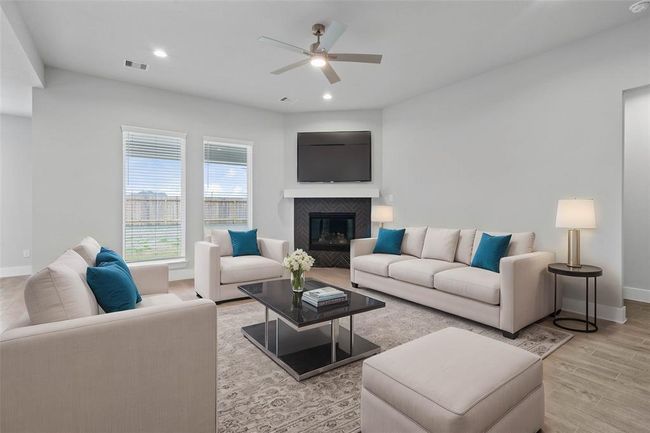 Gather the family and guests together in your lovely family room! Featuring fireplace with wood mantel, high ceilings with ceiling fan, recessed lighting, custom paint, beautiful wood-look tile floors, and large windows that provide plenty of natural lighting throughout the day. | Image 9