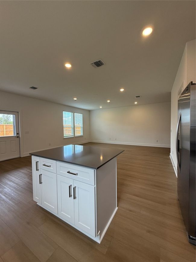 Kitchen featuring fridge, dark countertops, wood finished floors, white cabinetry, and recessed lighting | Image 16