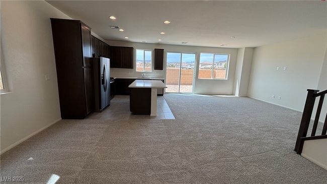 Kitchen with recessed lighting, stainless steel fridge, a kitchen island, light countertops, and light colored carpet | Image 6