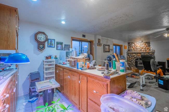 Kitchen featuring open floor plan, a wood stove, brown cabinets, light countertops, and a ceiling fan | Image 48