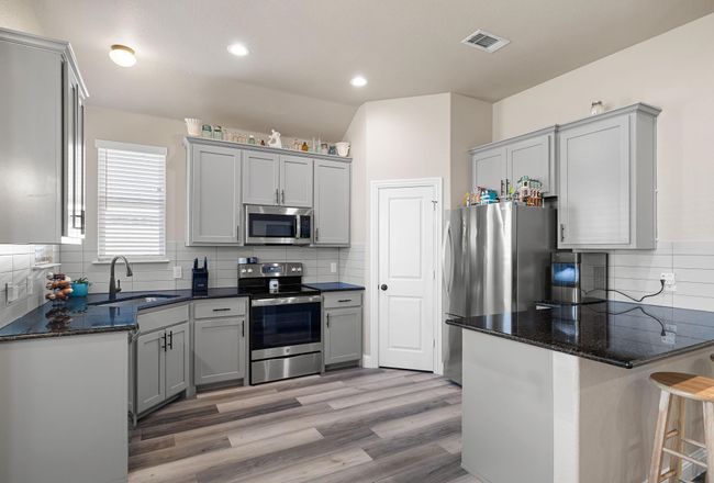 Kitchen with a sink, visible vents, stainless steel appliances, a peninsula, and backsplash | Image 13