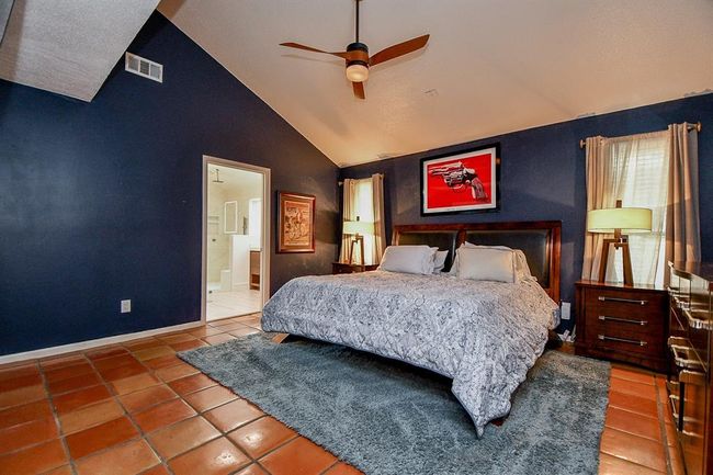 Warm and rustic in a contemporary way, this primary suite is your private oasis for rest and relaxation; with double windows, high ceiling, and plenty of wall and floor space, filled with rich adobe toned tile. Your ensuite bath peeks out, left. | Image 24