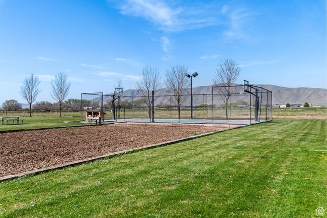 View of basketball court with community basketball court, a mountain view, fence, and a lawn | Image 13