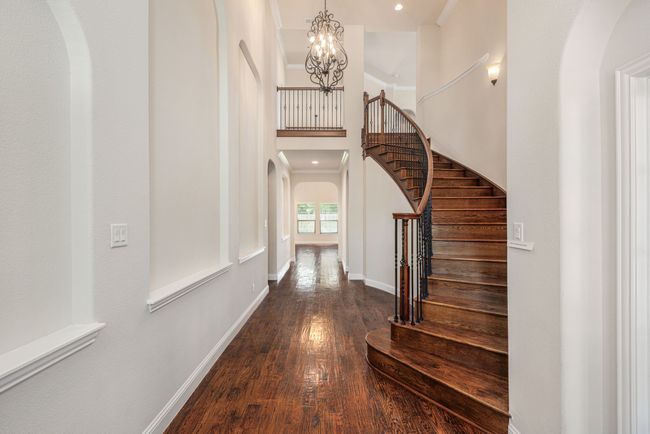 Foyer entrance with arched walkways, a chandelier, wood finished floors, and stairway | Image 13